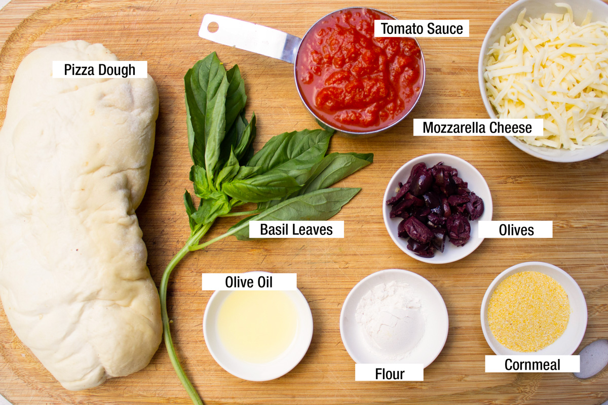 dough, tomato sauce, olive oil, basil leaves, flour, cornmeal, olives, cheese, tomato sauce