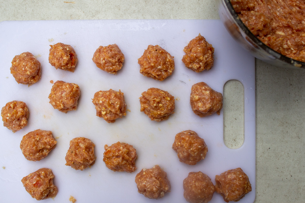 uncooked meatballs on cutting board.