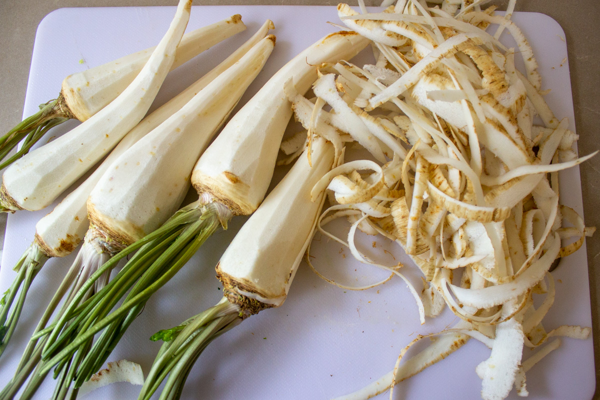 peeled parsnips with stems showing peelings on the side