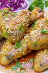pile of chicken wings on plate with honey garlic sauce and sesame seeds