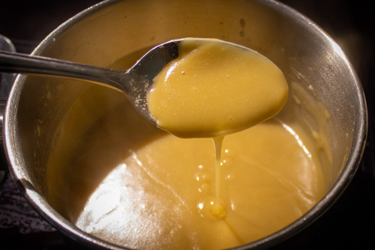 poutine gravy in pot dripping off a spoon