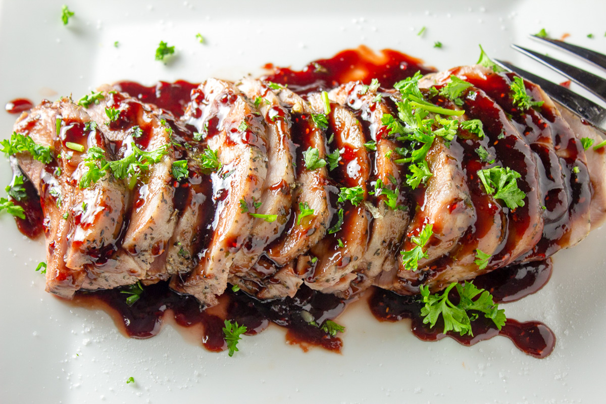 sliced pork loin with sauce on white plate
