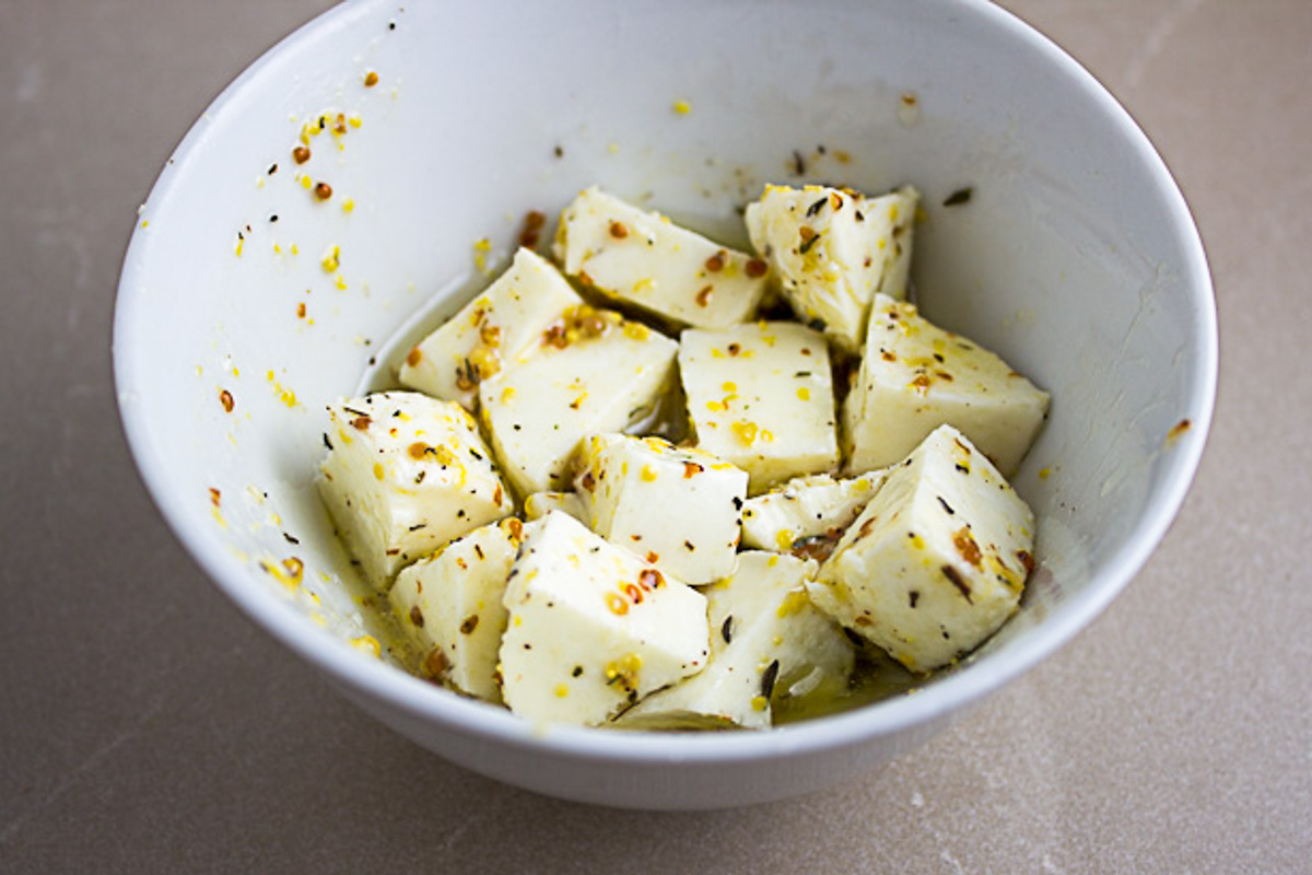 mozzarella cubes marinating in vinaigrette in small bowl