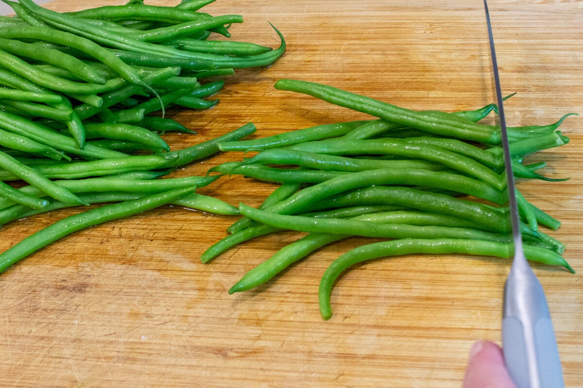 pile of beans with some getting ends trimmed with knife.