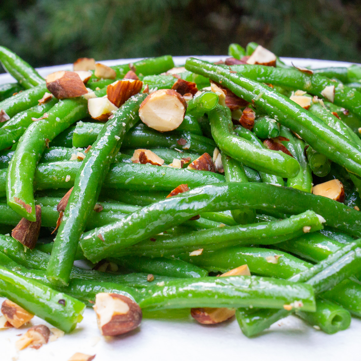 close up of green beans on plate with chopped nuts