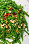green beans on white plate with chopped almonds on top