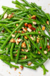 green beans on white plate with chopped almonds on top.