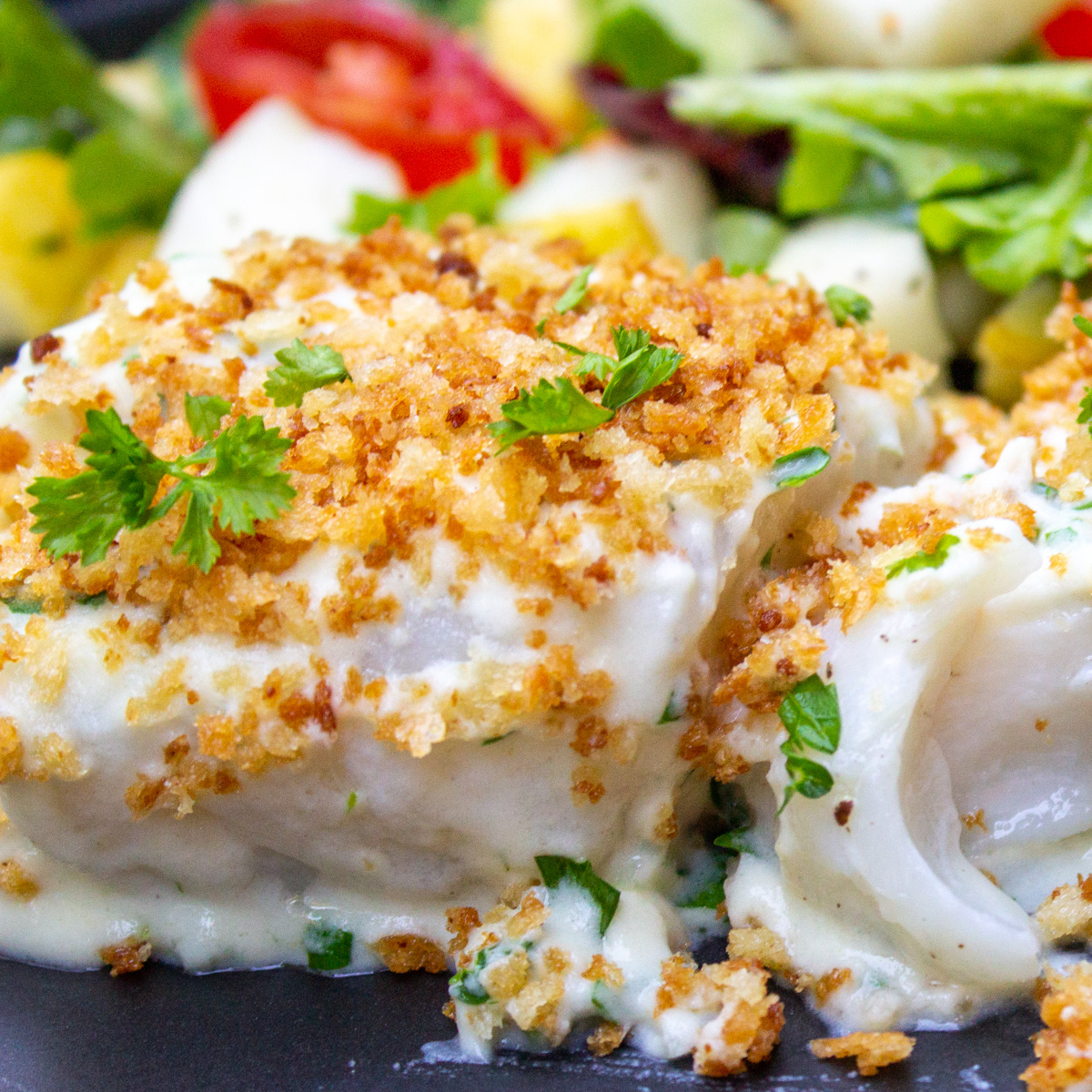 cod in bechamel sauce topped with panko with salad on plate