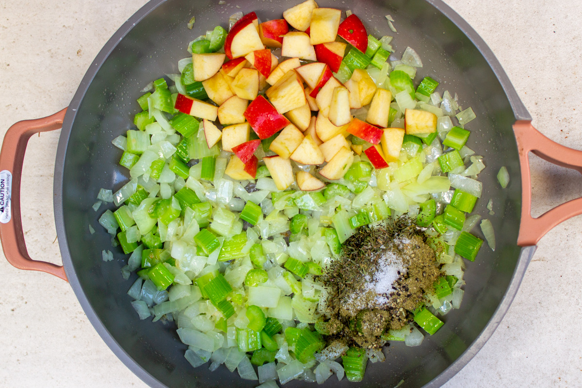 chopped veggies sauteeing in pan with seasonings and apples added