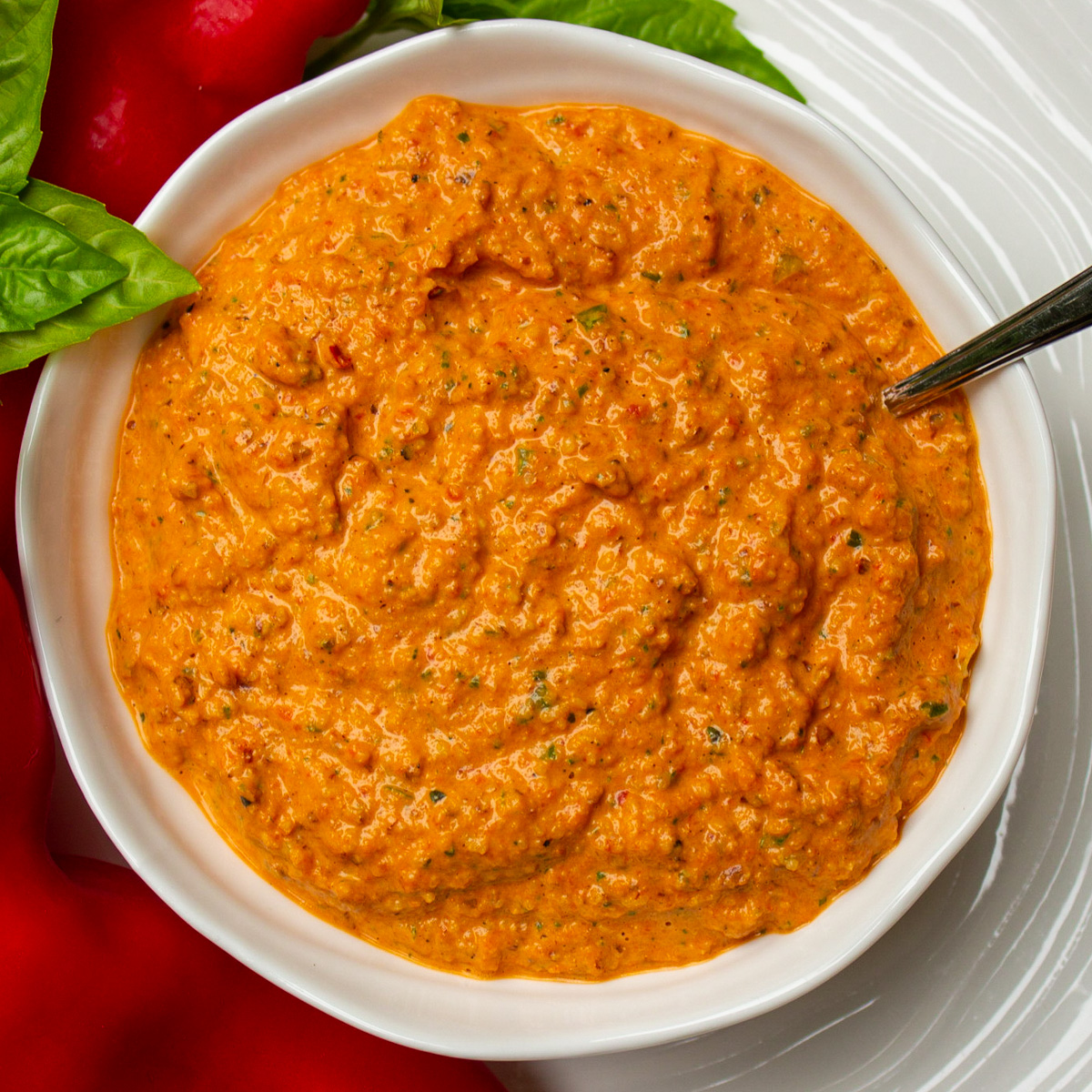 bowl of red pepper dip with fresh red pepper beside.