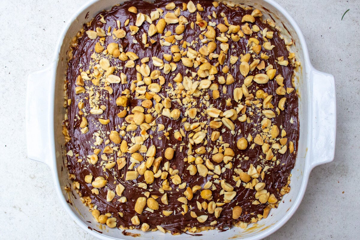 peanut butter rice krispie squares in plan iced with chocolate and peanuts
