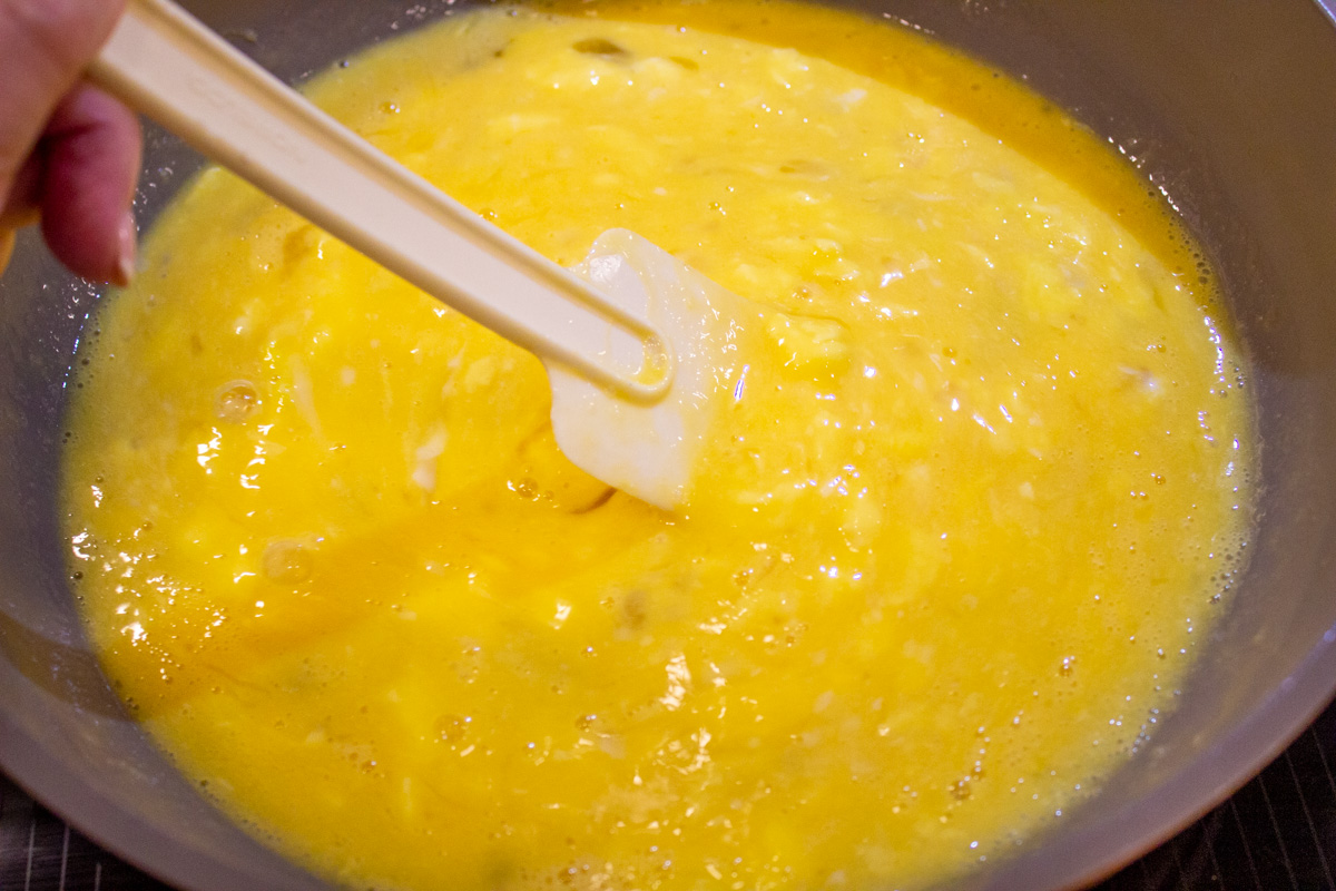 liquidy eggs stirred in skillet with rubber spatula