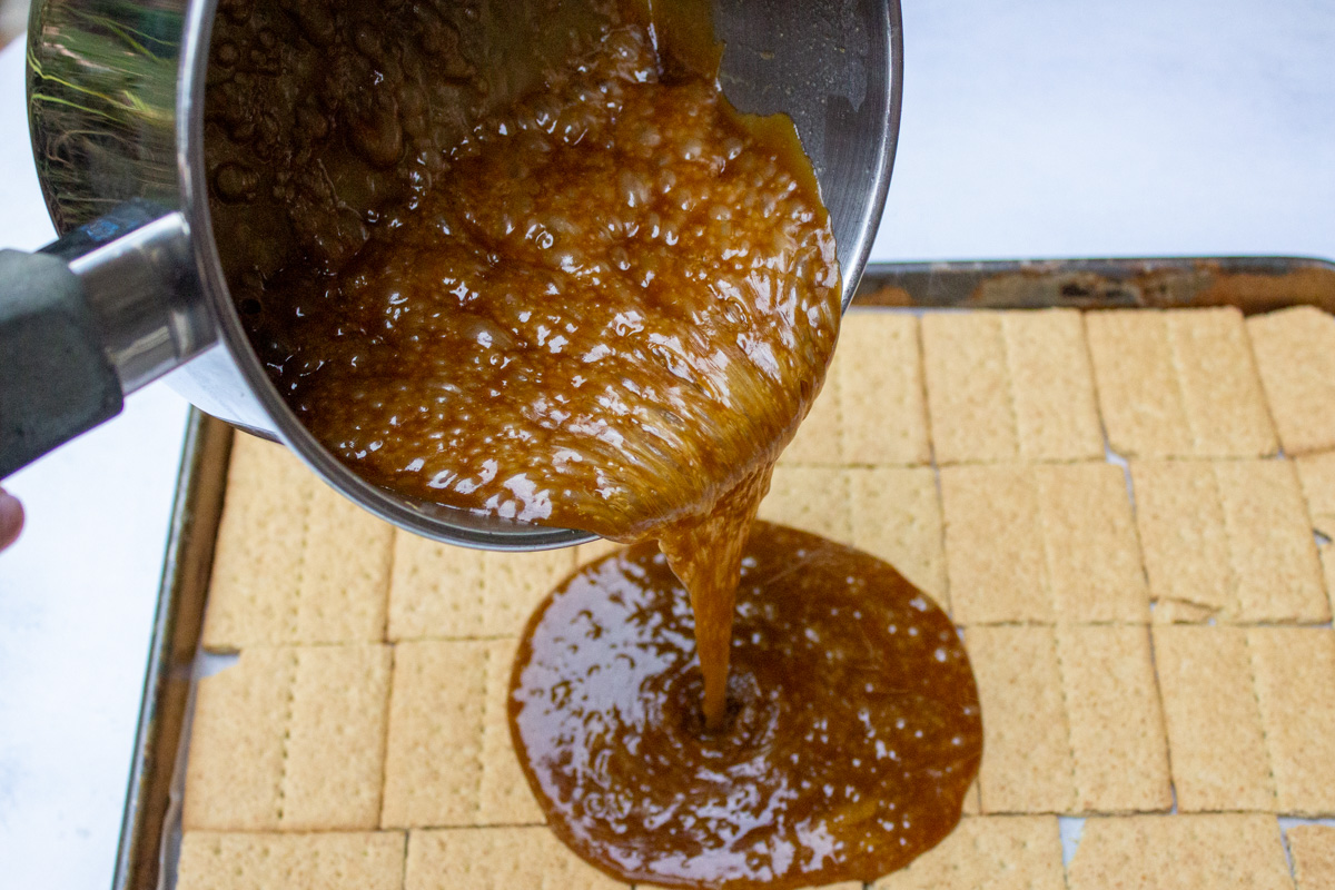 toffee mixture pouring onto graham crackers on pan