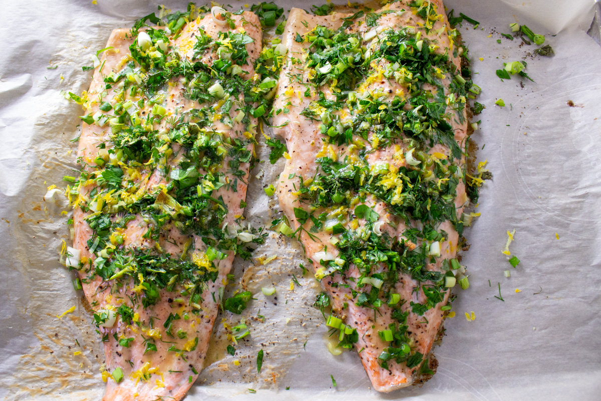 baked trout with herbs on parchment on pan