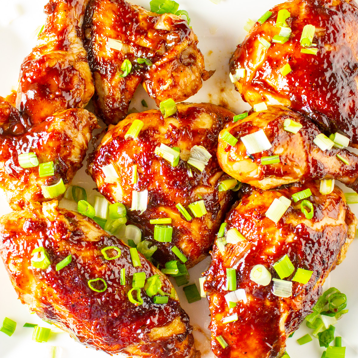 pieces of balsamic chicken on plate with green onion garnish