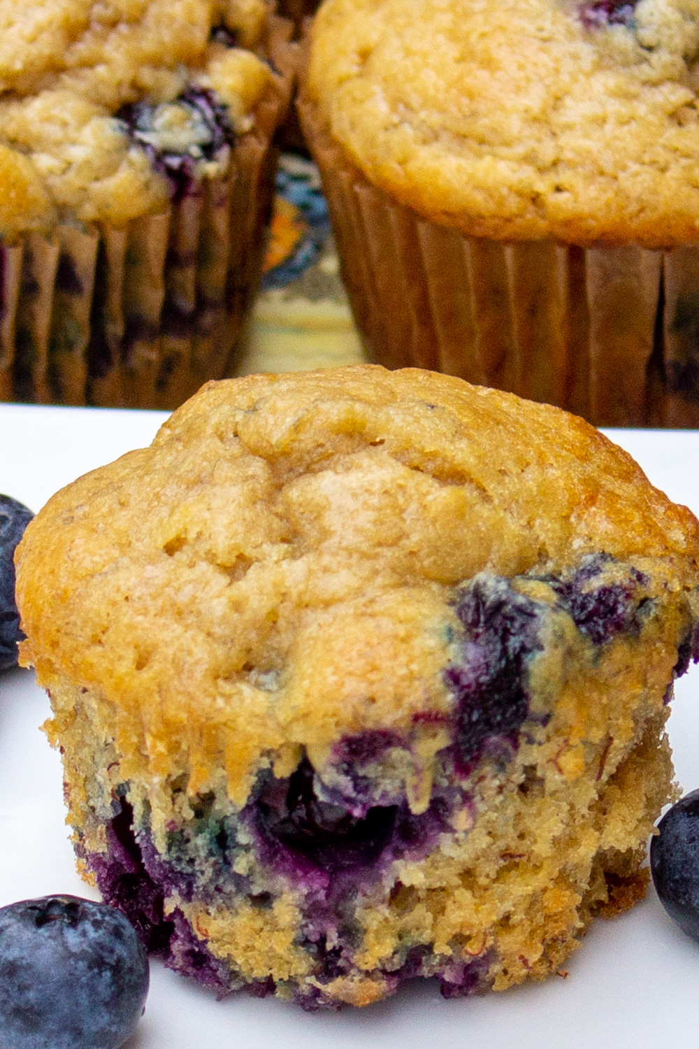 one banana blueberry muffin on plate with more muffins behind