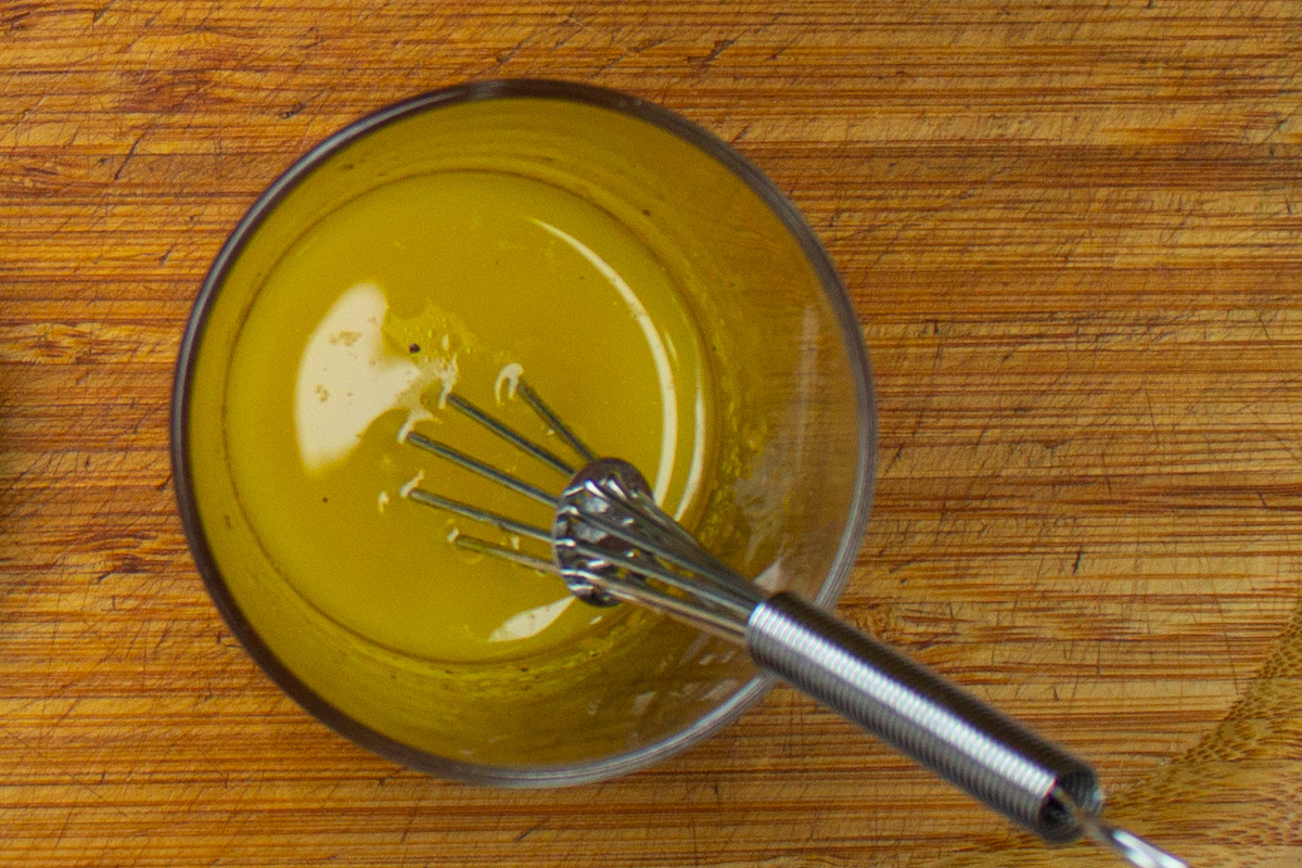 orange vinaigrette in small cup with whisk