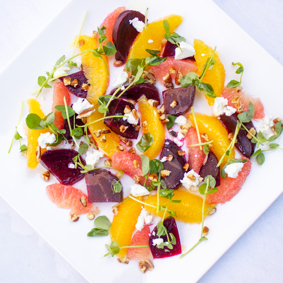 beetroot salad with citrus fruit and goat cheese on white plate