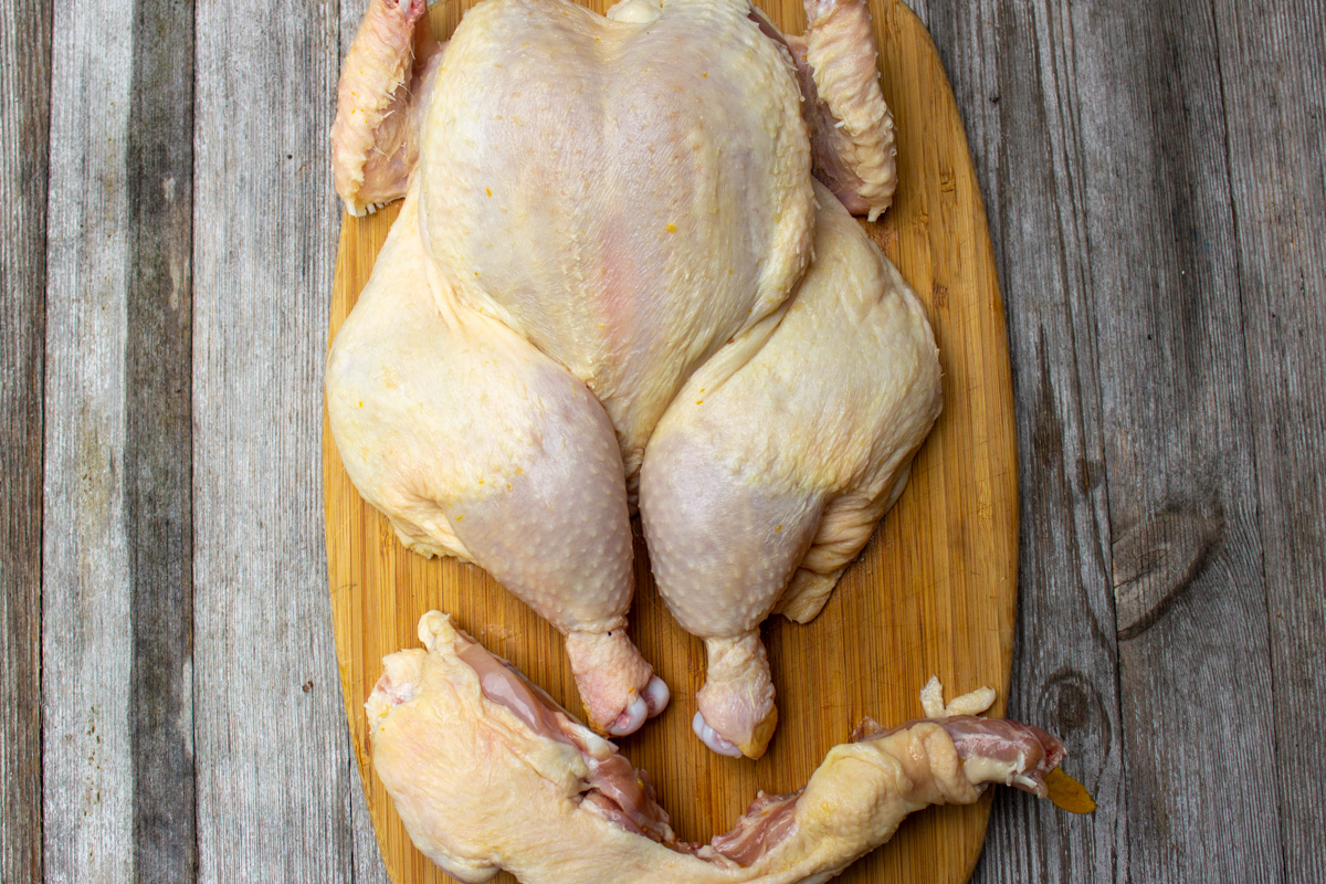 whole chicken with backbone removed and flattened on cutting board.