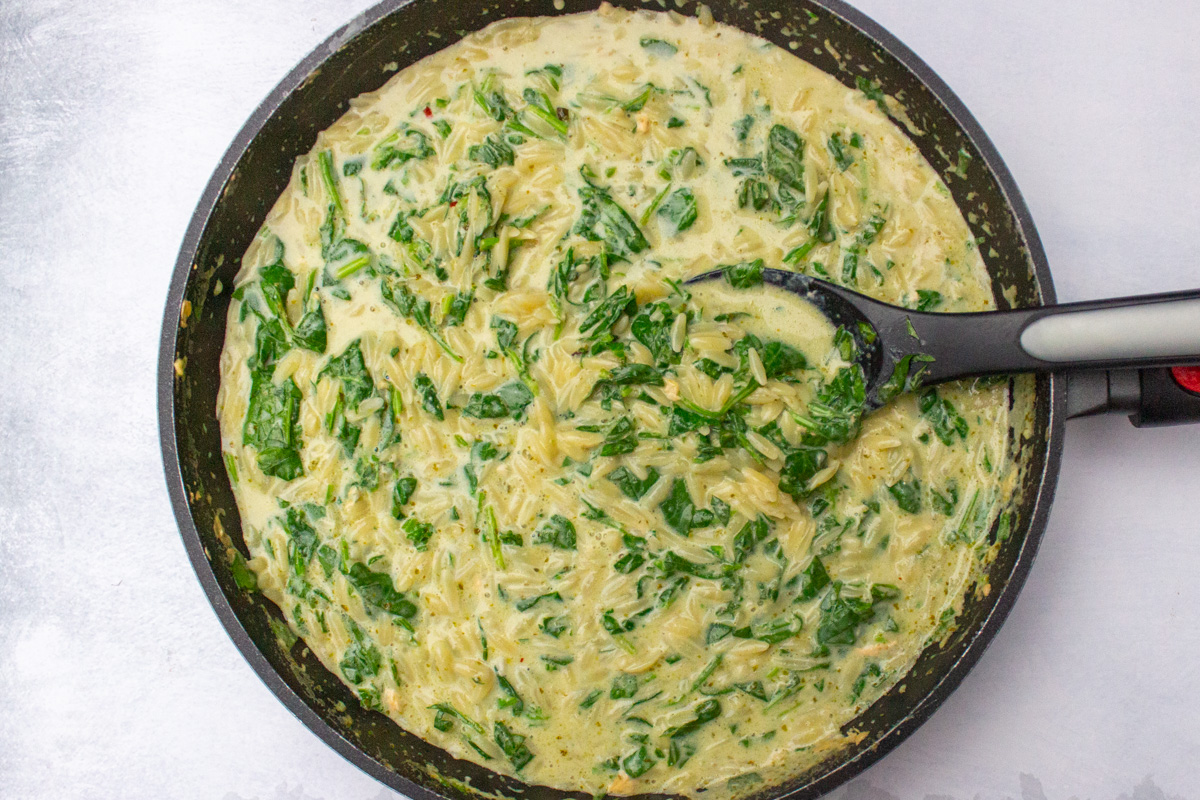 orzo, cream sauce and spinach cooked in skillet