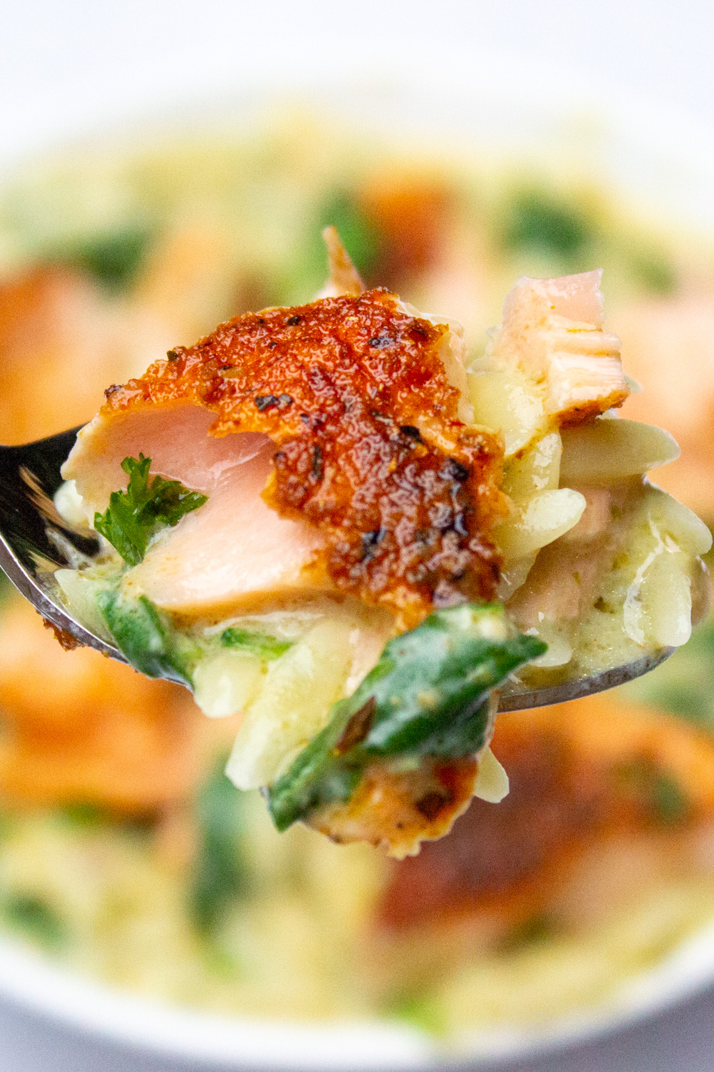 forkful of salmon orzo pasta and spinach over bowl
