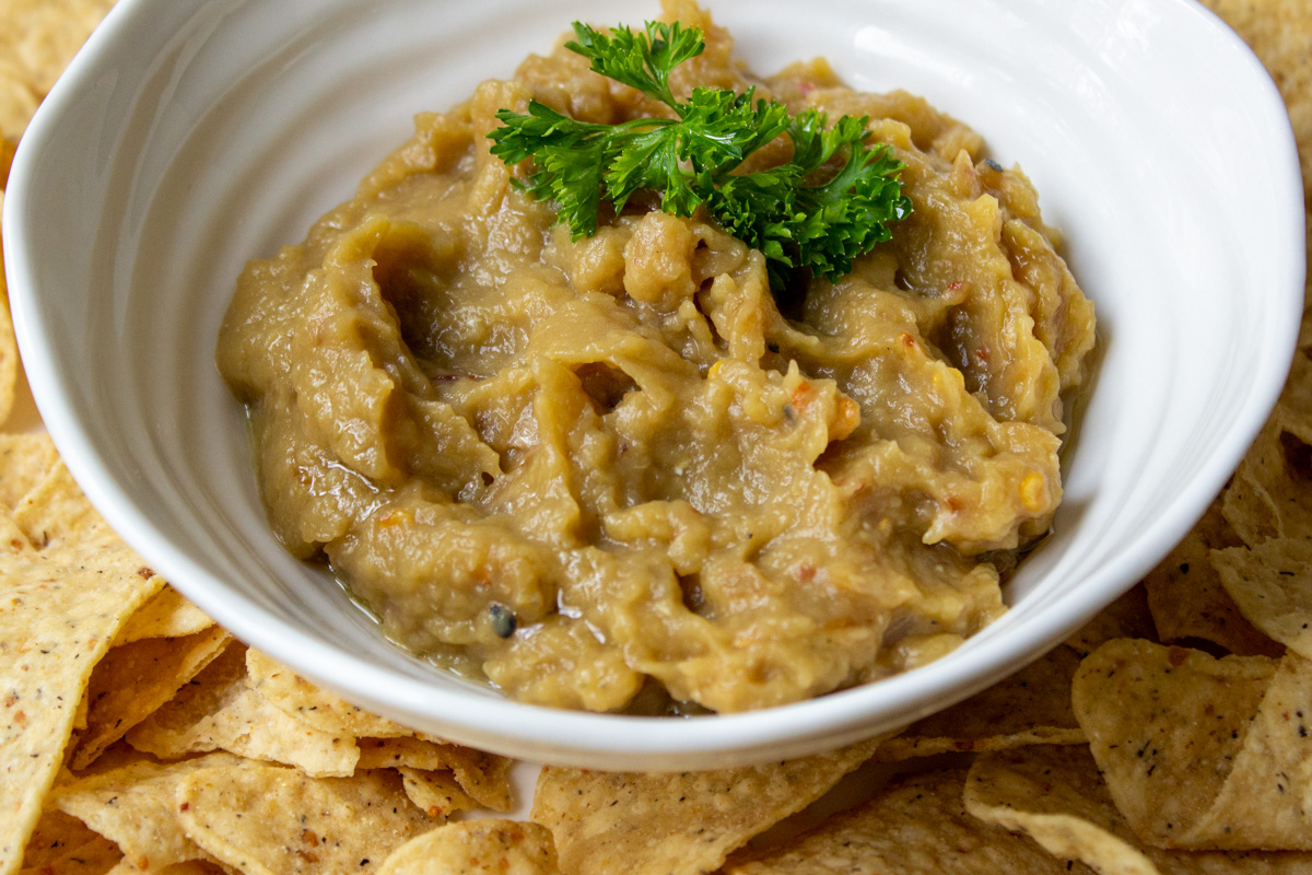 eggplant dip in white bowl with corn chips