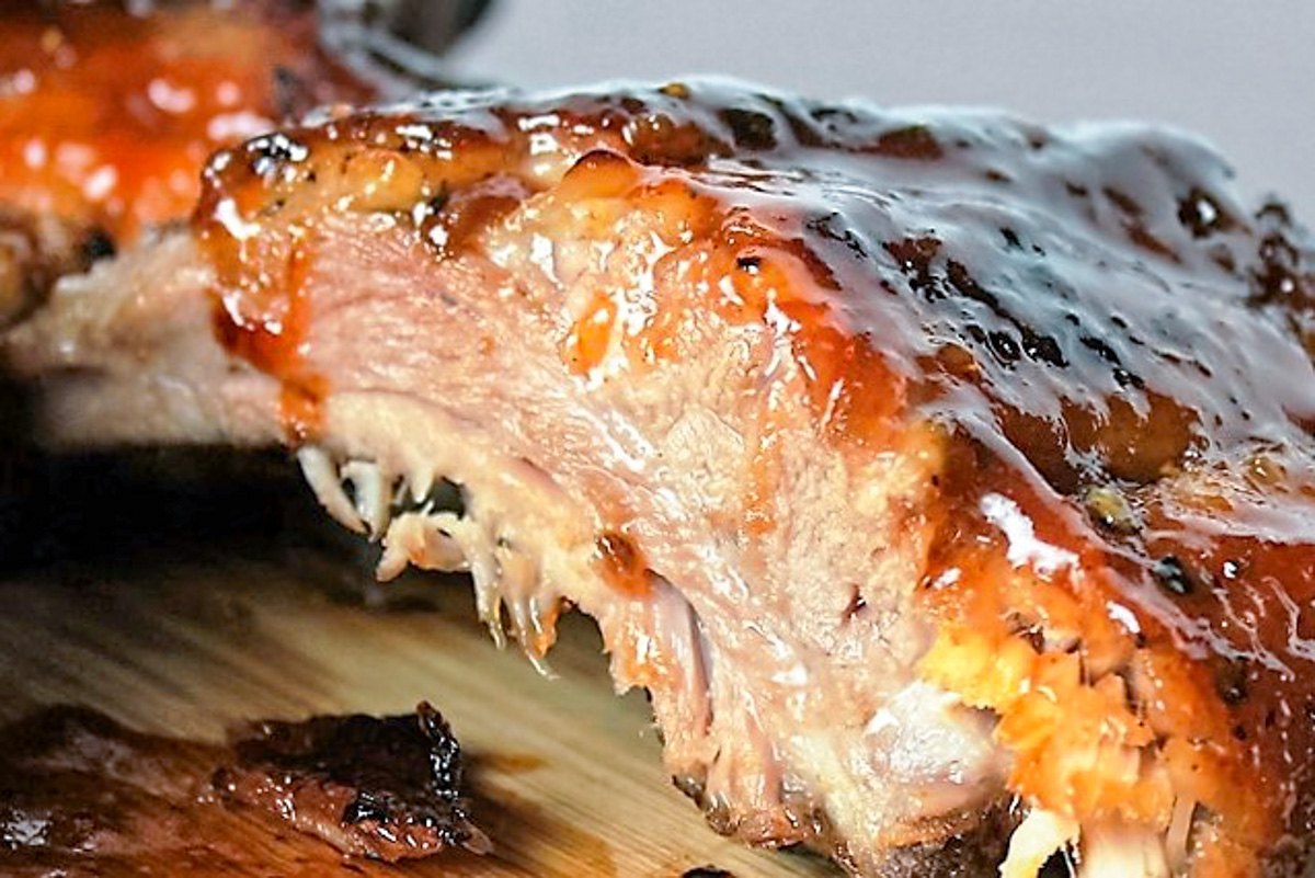 close up of one glazed rib with tender meat on cutting board