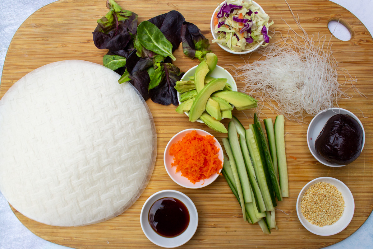 rice paper wrappers, grated carrots, hoisin sauce, lettuce leaves, chopped cabbage, sliced avocado, rice vermicelli, sesame seeds