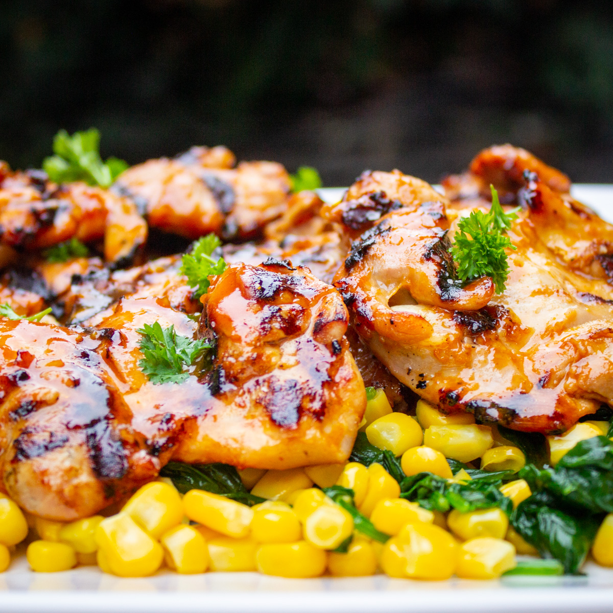 grilled chicken thighs over corn on plate
