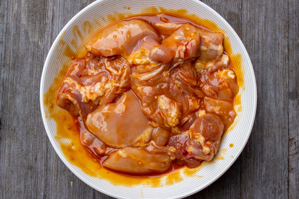 chicken thighs in bowl marinating in sauce