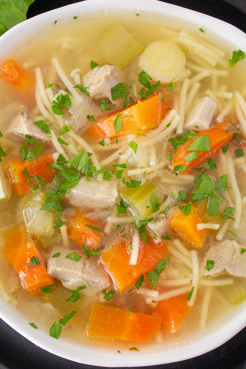 bowl of turkey soup with vegetables and noodles.