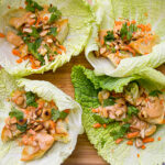 4 lettuce wraps with dumplings and peanut sauce and garnish.