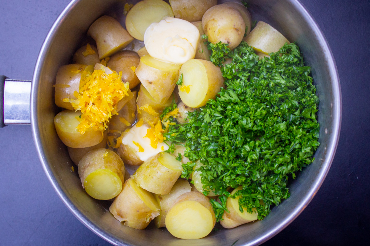 parsley zest butter and salt on top of cooked potatoes in pot