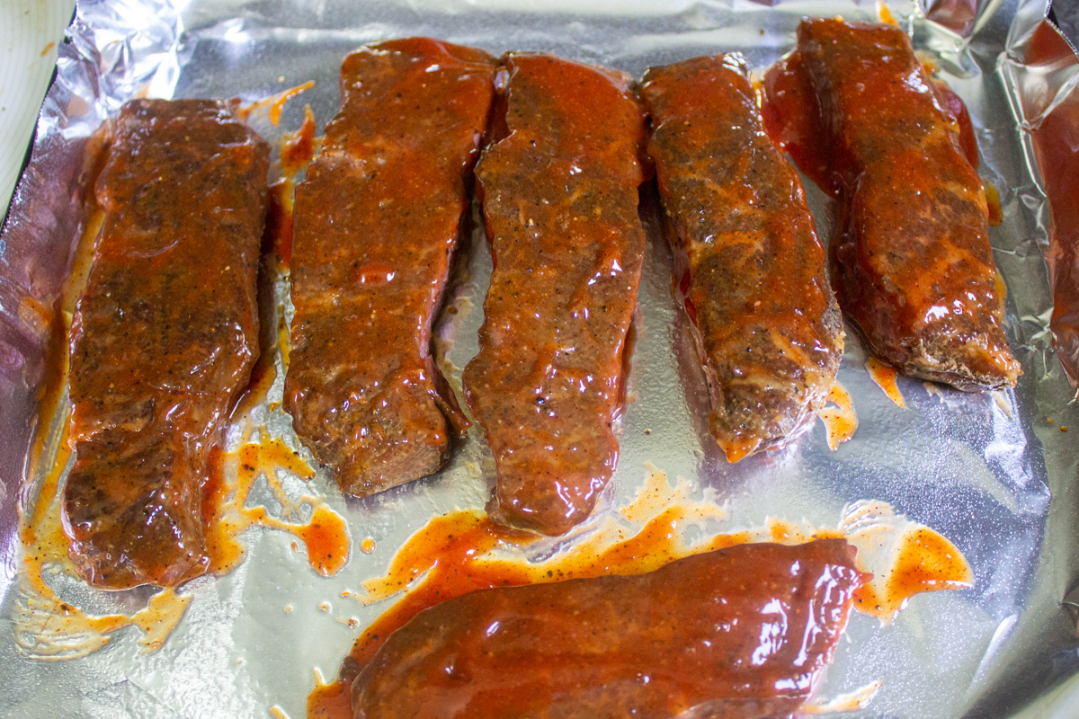sous vide cooked ribs with bbq sauce on pan before final grilling.