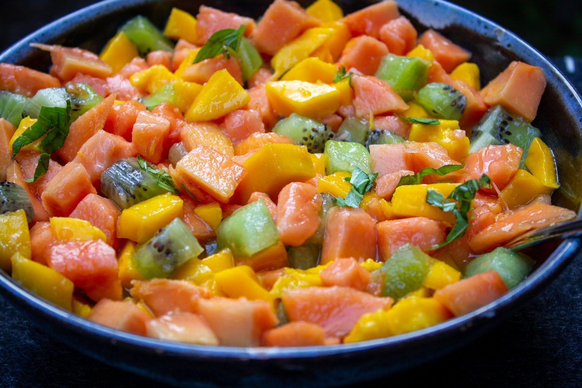 bowl of tropical fruit salad with fresh orange juice.