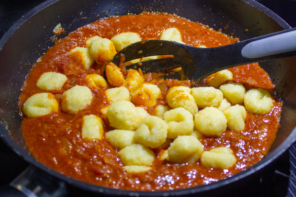 cooked gnocchi added to sauce in skillet