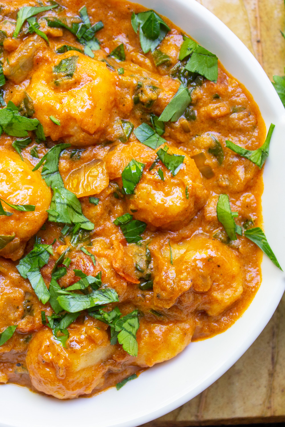 veg gnocchi in an indian sauce with spinach in white bowl