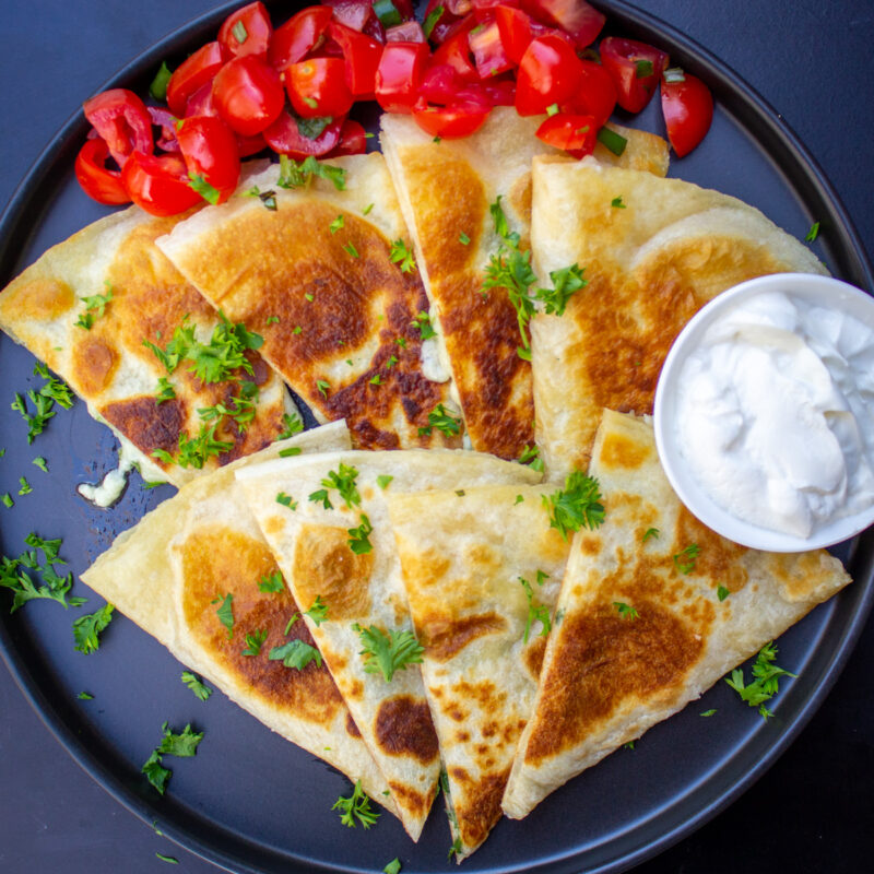 cheese quesadilla wedges on plate with sour cream.