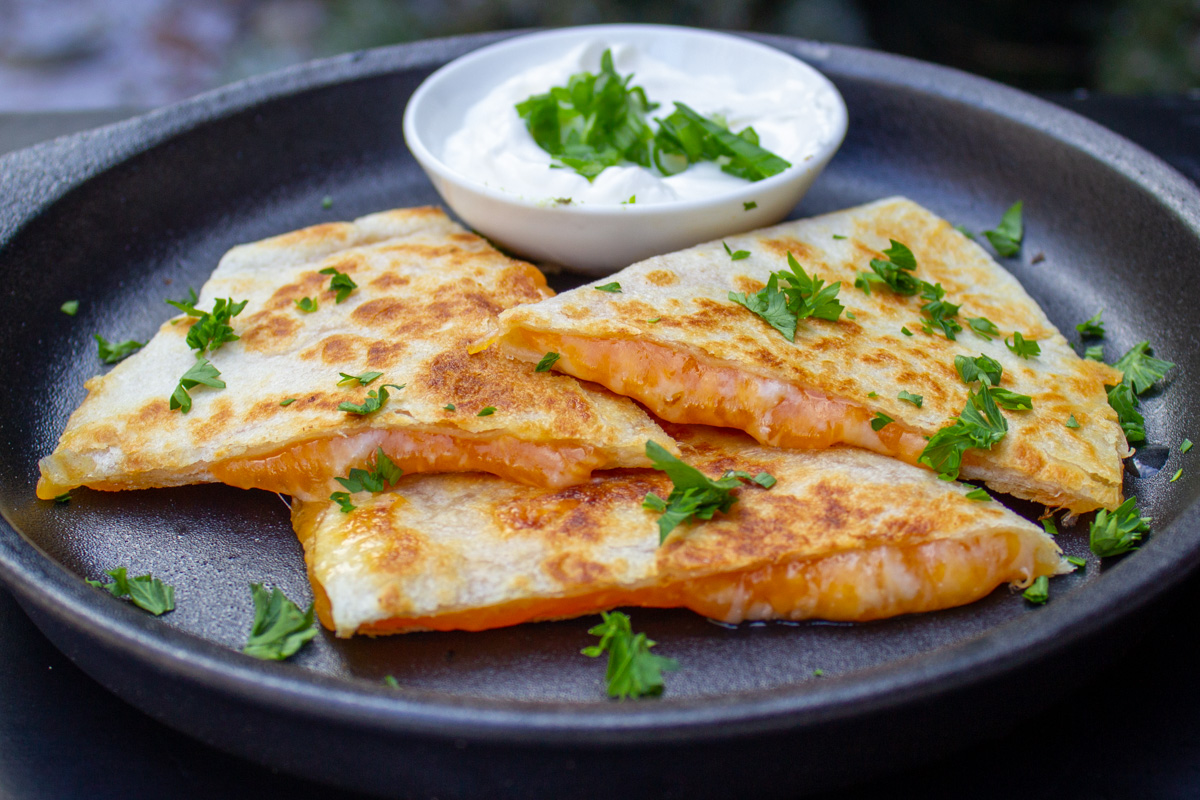 cheese quesadilla wedges on plate with sour cream.