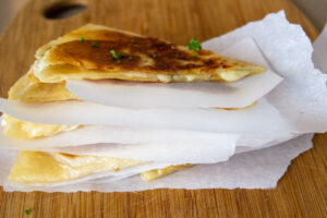 quesadilla wedges separated by parchment paper in a stack.