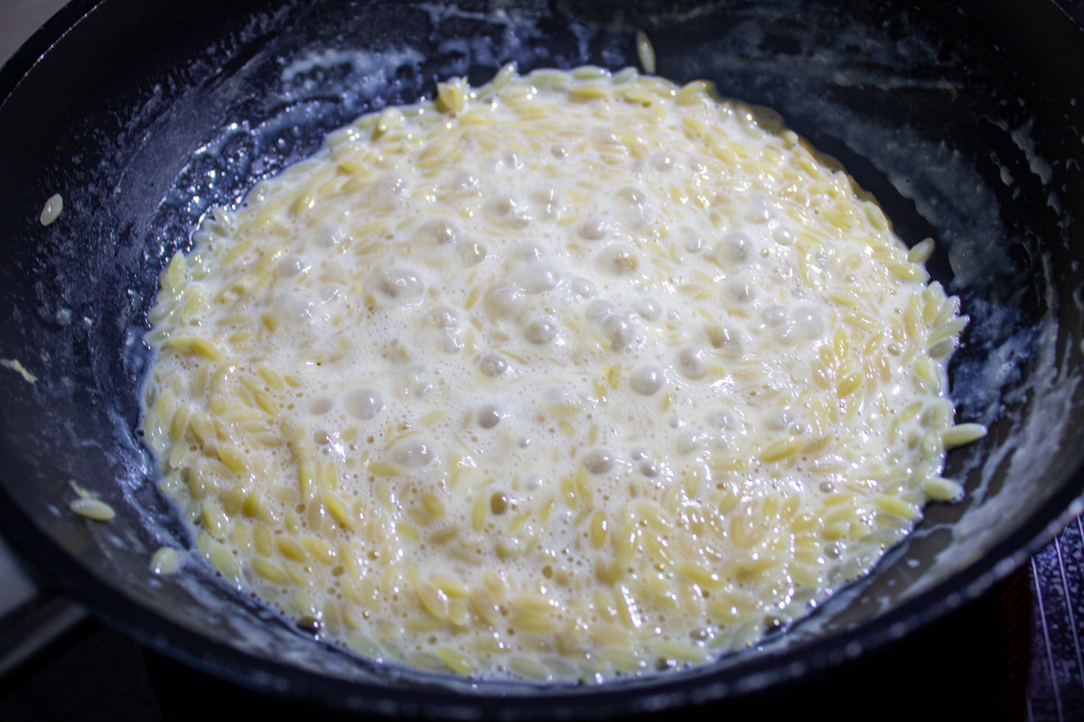 orzo, milk and broth cooking in skillet