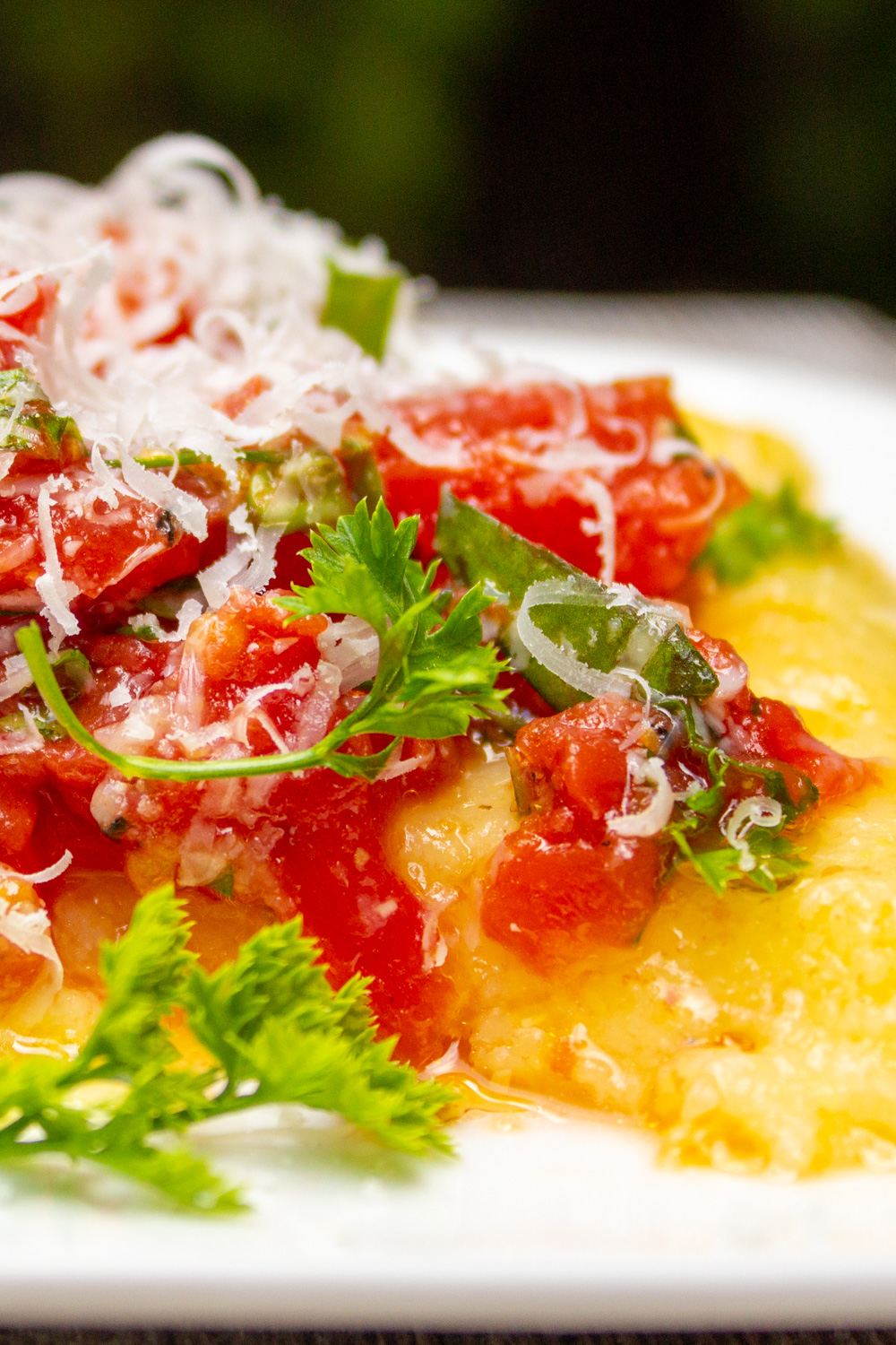 plate of polenta covered with tomato salad and parmesan.