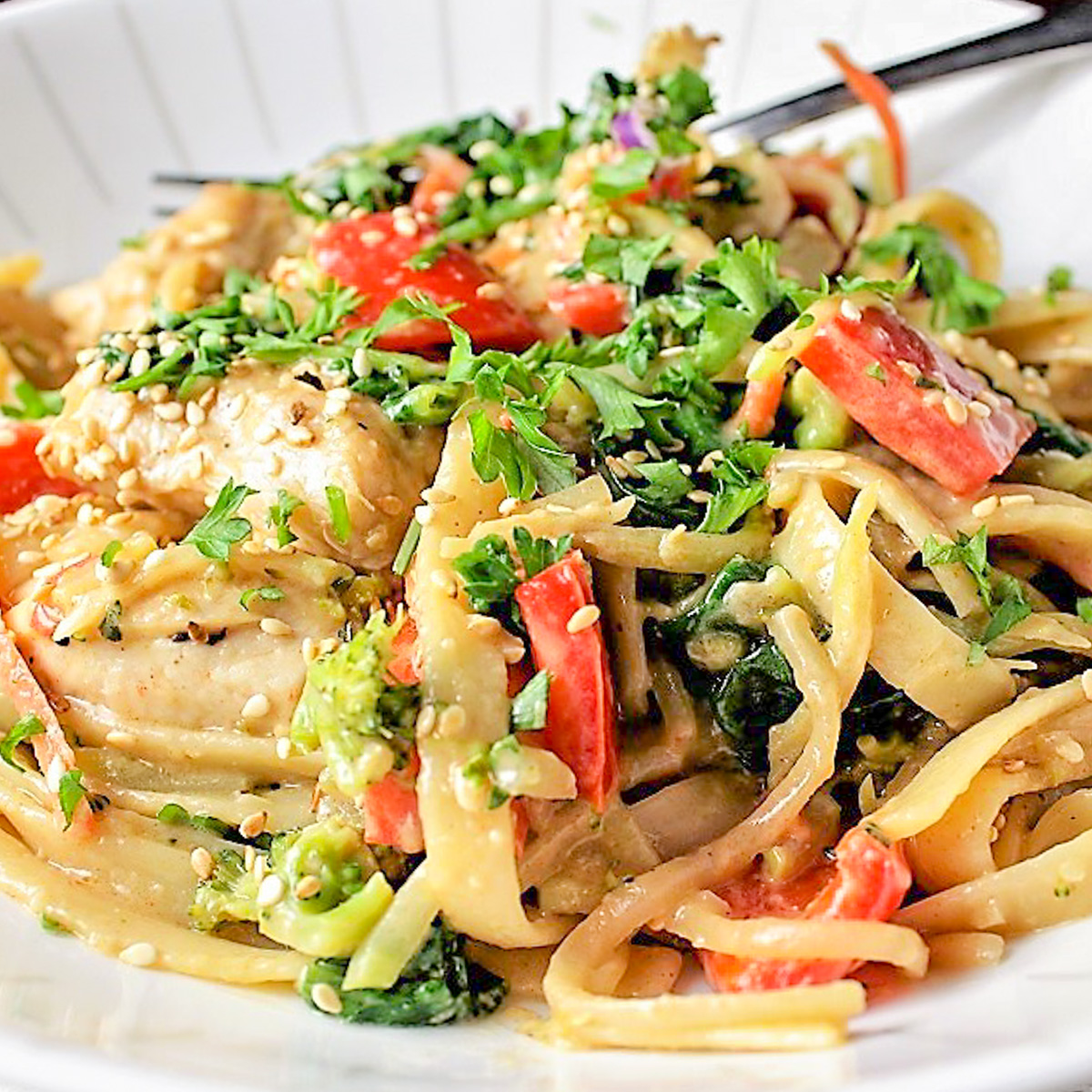 peanut chicken with veggies and noodles on a plate.