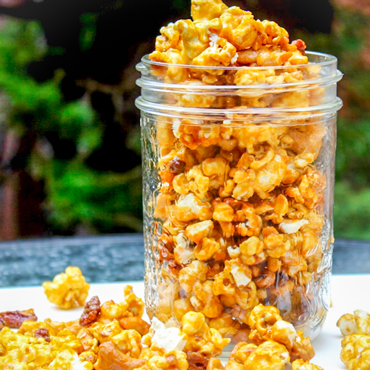 salted caramel popcorn in a tall clear jar on table.