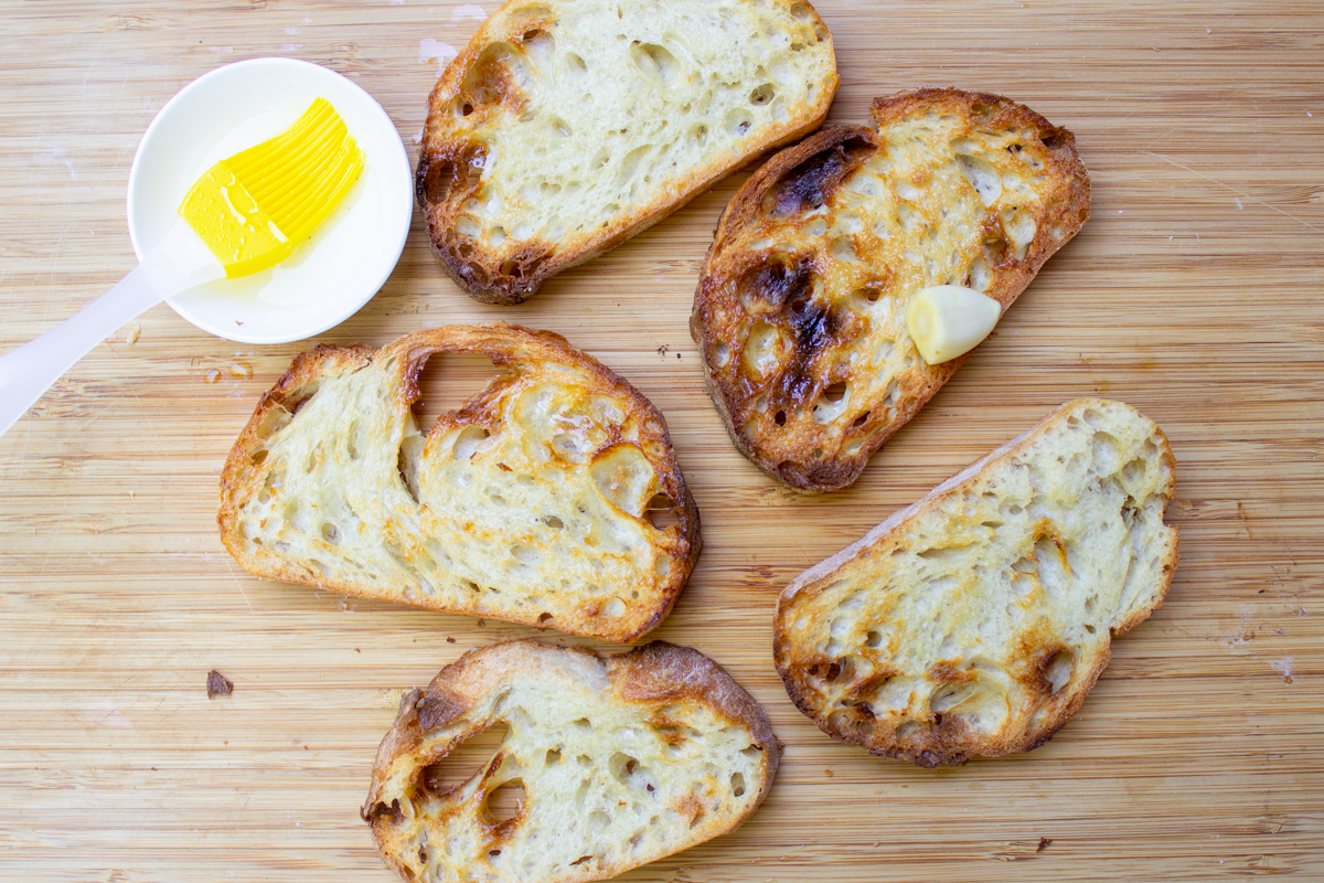 toasted bread slices with olive oil on cutting board.