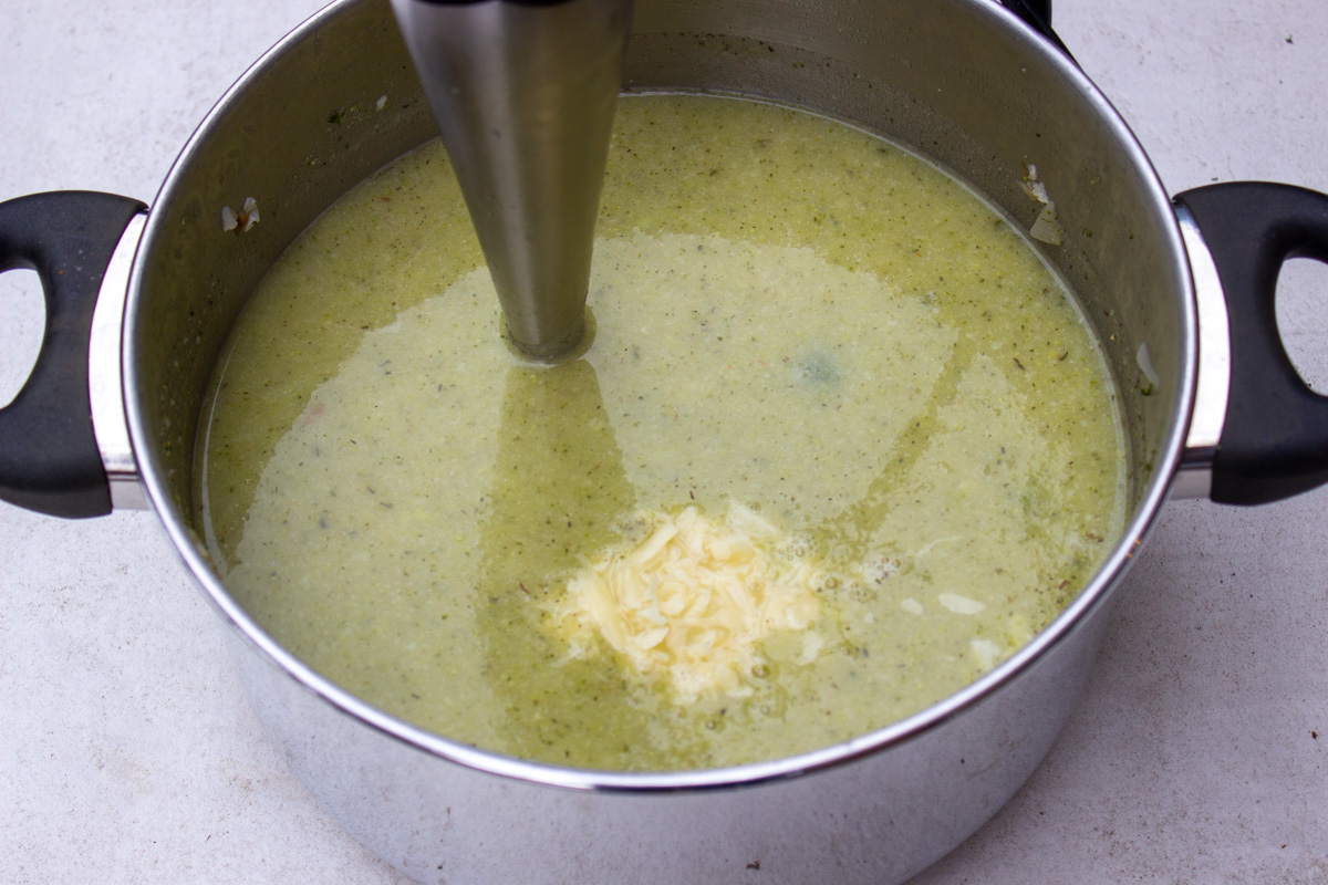pureed broccoli and cauliflower soup in pot with immersion blender. Cheese added.