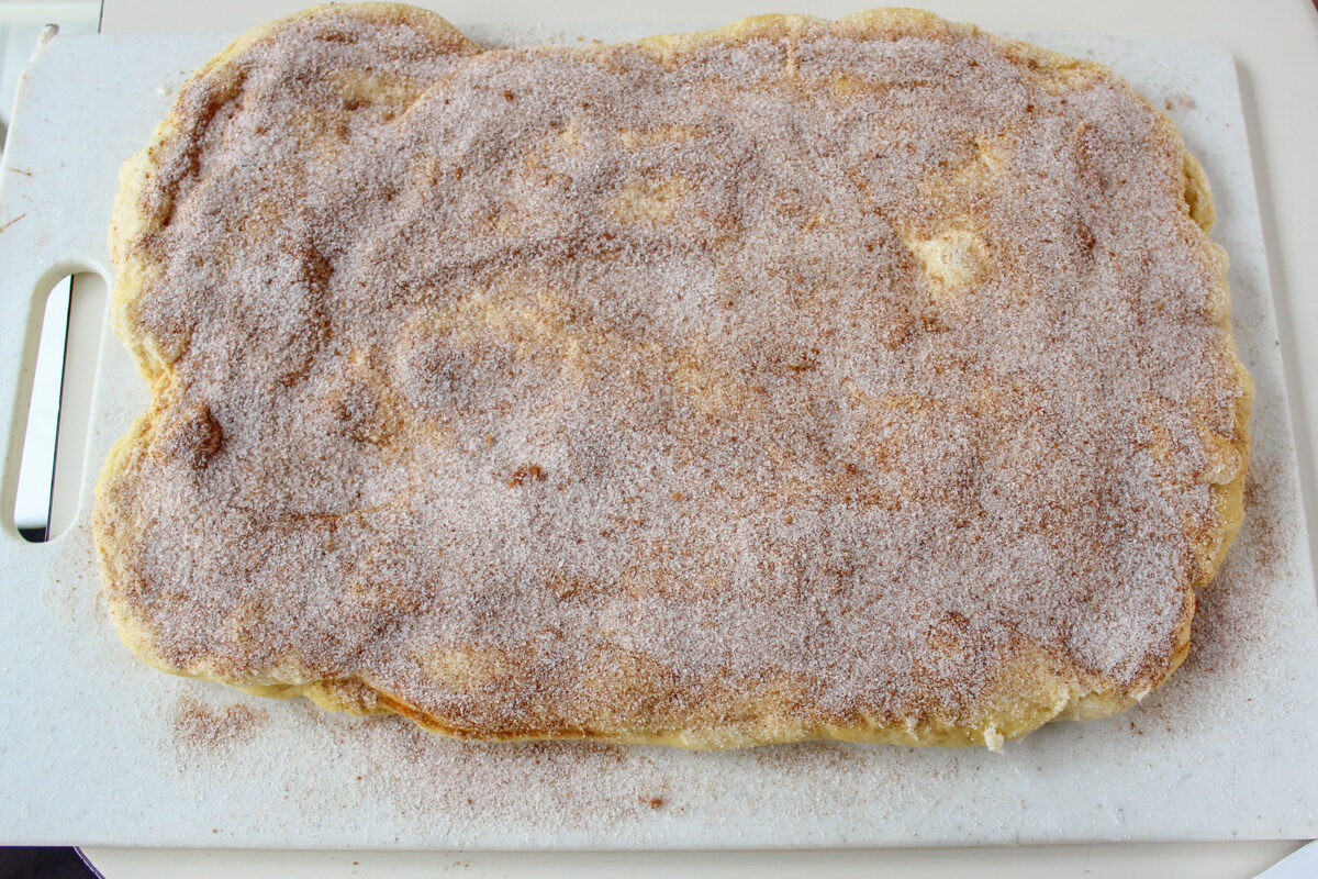 cinnamon sugar mixture and butter on rolled out dough