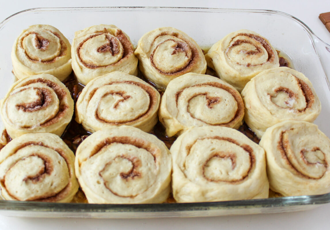 uncooled cinnamon roll pieces in pan, swirl sides up.