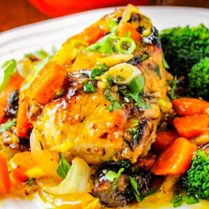 company chicken breast with carrots citrus and pistachios with broccoli on plate.