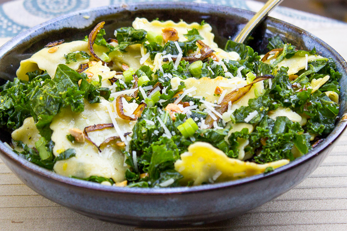 kale slaw tossed with ravioli in a bowl.